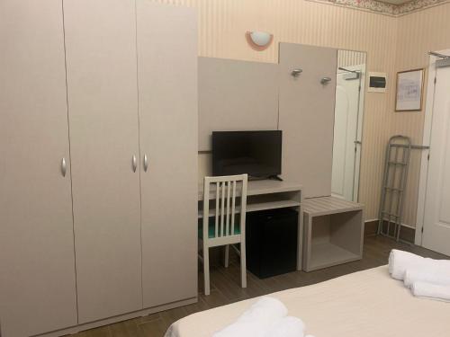 a bedroom with a desk with a television and a bed at Hotel Royal Plaza in Rimini