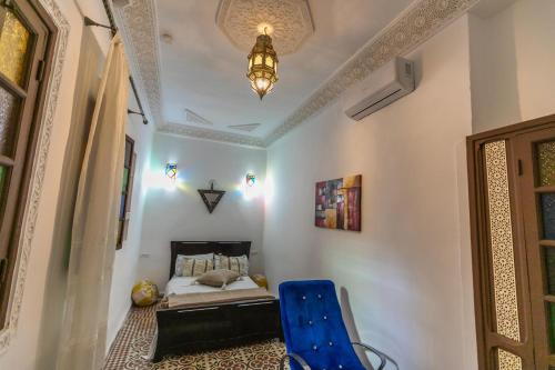 a bedroom with a bed and a blue chair at Riad bel kayed in Fès