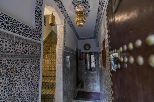 a hallway of a mosque with a chandelier and tiles at Riad bel kayed in Fès
