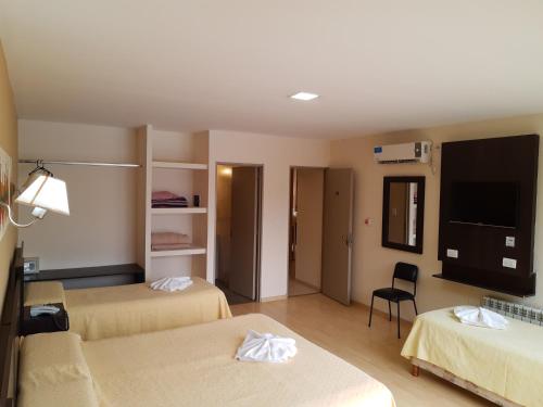 a hotel room with two beds and a flat screen tv at Hotel Presidente in Villa Carlos Paz