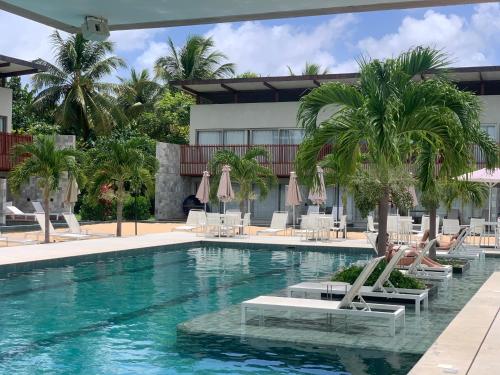 uma piscina com cadeiras e palmeiras e um prédio em Ilê de Pipa Blz em Pipa