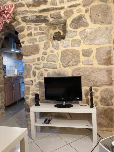 einen TV auf einem weißen Tisch vor einer Steinmauer in der Unterkunft L'Atelier de la Forge La forge in Martigny-le-Comte