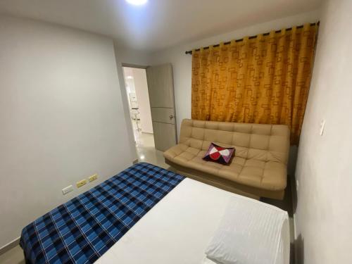 een kleine kamer met een bank en een bed bij Apto a pasos del lago in Guatapé