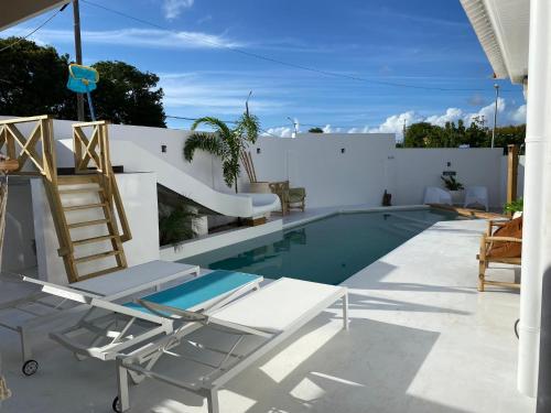 a swimming pool with chairs and a ladder next to a house at 4BlessingsCuracao2 in Willemstad