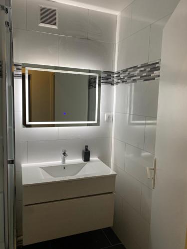 a white bathroom with a sink and a mirror at Appartement Ping-Pong proche gare Gagny in Gagny