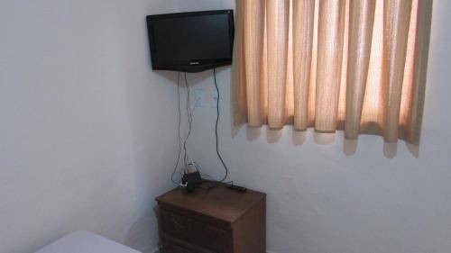 Habitación con TV en la pared y tocador de madera. en Pousada Rústica en São Tomé das Letras