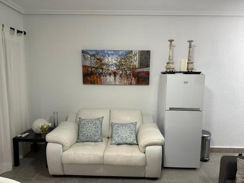 a living room with a white couch and a painting at Bungalow Santa Pola del Este in Gran Alacant