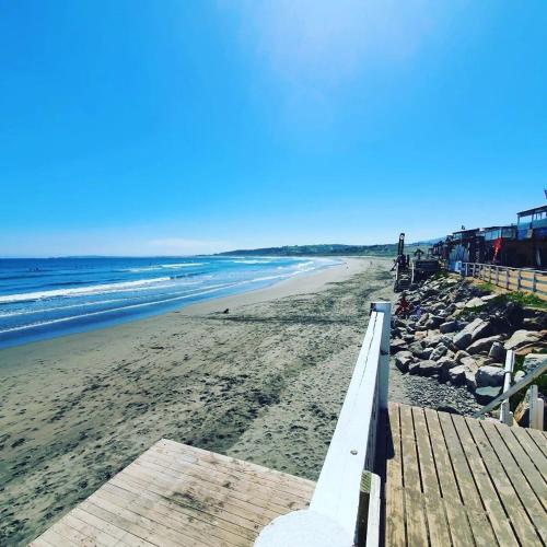 a beach with a wooden pier and the ocean at Bocamar Aparthotel in Viña del Mar