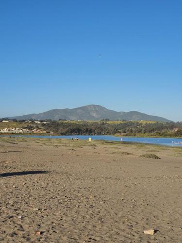 a sandy beach with water and mountains in the background at Bocamar Aparthotel in Viña del Mar