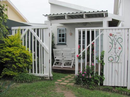 a white gate with a pergola on a house at Rose and Ale Self Catering Units in Gonubie