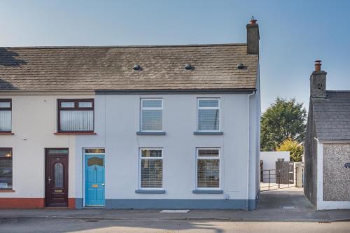 a white house with blue doors and windows at The Innkeeper’s Lodge Bushmills in Bushmills