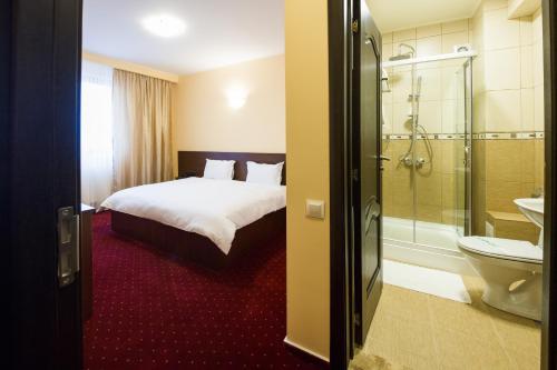 a hotel room with a bed and a bathroom at Hotel Athos in Bucharest