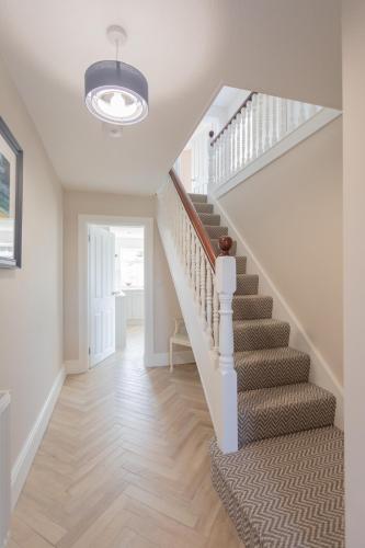 a staircase in a home with a white stair case at The Innkeeper’s Lodge Bushmills in Bushmills