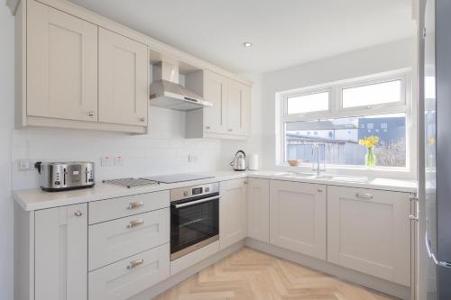 a white kitchen with white cabinets and a window at The Innkeeper’s Lodge Bushmills in Bushmills