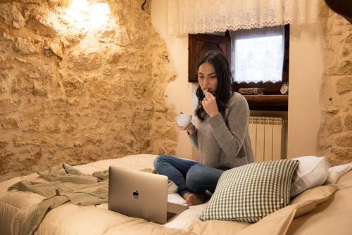 een vrouw op een bed met een kopje koffie en een laptop bij Aremogna - Dimora Rosy in Roccaraso