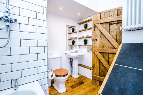 a bathroom with a barn door and a toilet at Ivy House Luxury Cheshire Cottage for relaxation. Chester Zoo· in Saughall