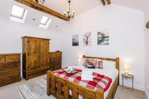 a bedroom with a wooden bed with a red and white blanket at Ivy House Luxury Cheshire Cottage for relaxation. Chester Zoo· in Saughall