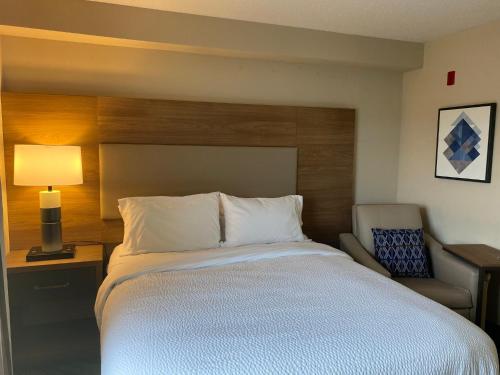 a bedroom with a large bed and a chair at Candlewood Suites Harrisburg I-81 Hershey Area by IHG in Harrisburg