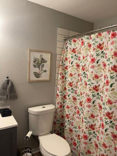a bathroom with a toilet and a flower shower curtain at The Deannie Apt #6 - Simple and Homey 2bd w/ WiFi in Hamilton