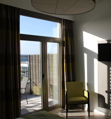 a room with a chair and a sliding glass door at Mondo hôtel in Tubize