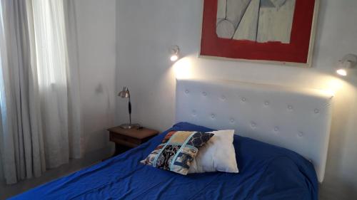 1 dormitorio con cama azul y almohada en Alquilo departamento en Zona La Perla en Mar del Plata