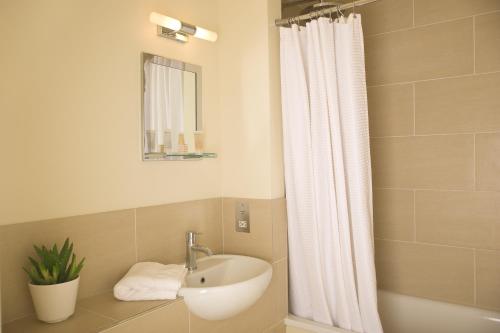 a bathroom with a sink and a shower curtain at The Marquess of Exeter in Uppingham