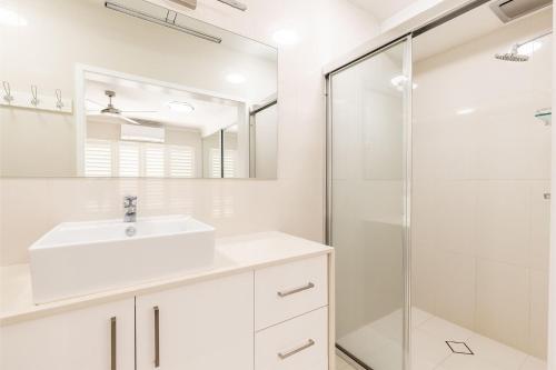 y baño blanco con lavabo y ducha. en Sandy Beach House Corlette Unit 1 Waterfront WI-FI Aircon, en Corlette