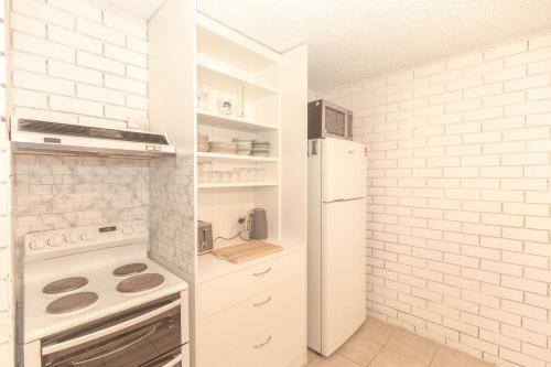 a kitchen with white appliances and a white brick wall at Sunrise 15 in Jindabyne