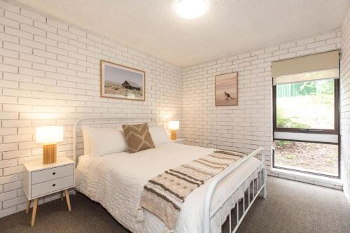 a white bedroom with a bed and a window at Sunrise 15 in Jindabyne