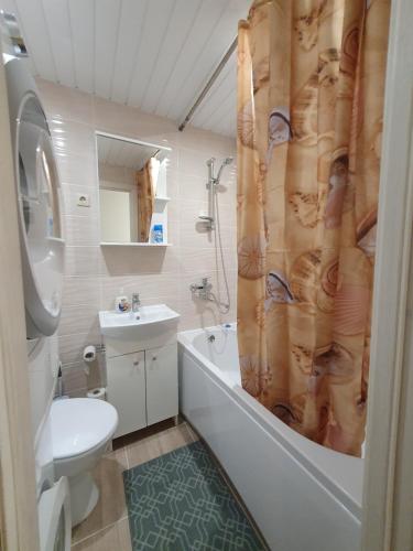 a bathroom with a tub and a toilet and a sink at Dainai 1-Bedroom apartament. in Šiauliai