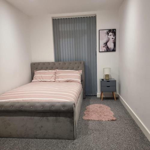 a bedroom with a bed with pink sheets and a nightstand at Classic 2 bed apartment in oldkent road in London
