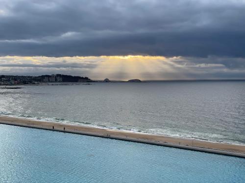 a view of the ocean and a pool with the sun shining at San Alfonso Mágico in Algarrobo
