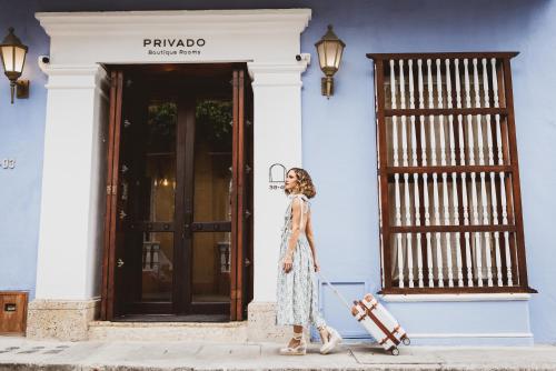 a woman walking down a sidewalk with a suitcase at Privado Designer Boutique Hotel in Cartagena de Indias