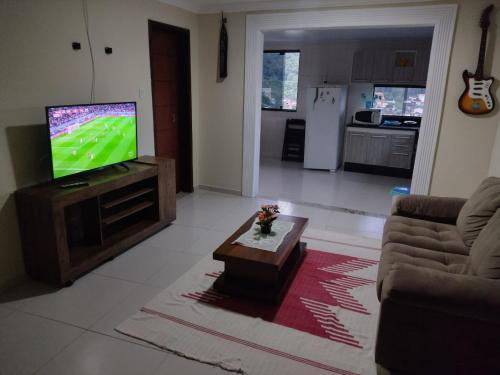 a living room with a television and a coffee table at Hospedagem da Val in Angra dos Reis