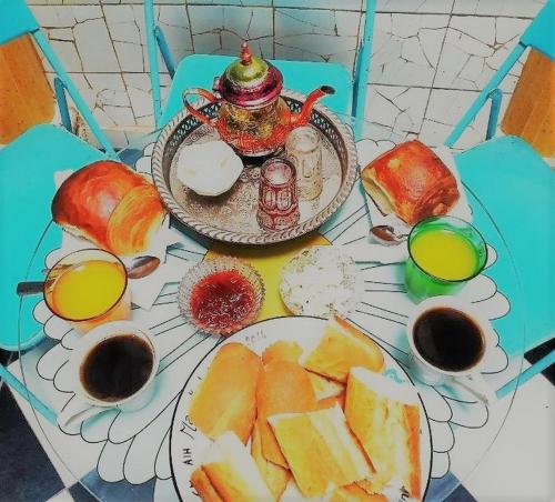 une table avec des assiettes de nourriture et des tasses de jus d'orange dans l'établissement Dar Alouane, à Essaouira