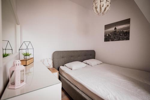 biała sypialnia z łóżkiem i żyrandolem w obiekcie Ottimo Apartamenty Floriana w Bydgoszczy