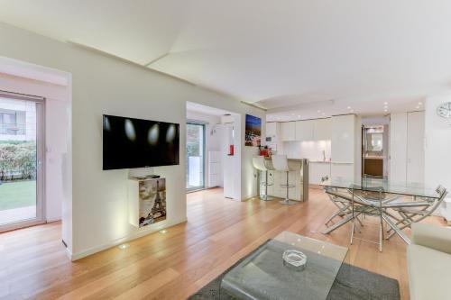 een woonkamer met een tafel en een tv aan de muur bij Appartement Standing à Toulouse en centre ville in Toulouse