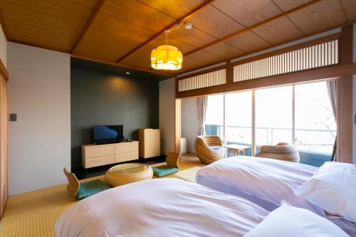 a bedroom with two beds and a television in it at Ryokan Yoshidaya in Ureshino