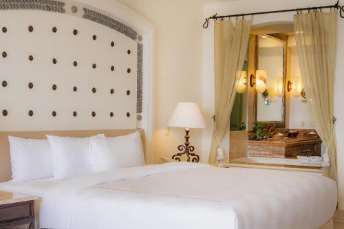 a bedroom with a large white bed and a mirror at Marquis Los Cabos, an All - Inclusive, Adults - Only & No Timeshare Resort in San José del Cabo