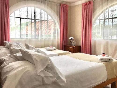 2 camas en un dormitorio con cortinas rojas y ventana en Casa con amplio jardín y alberca, en Tenango de Arista