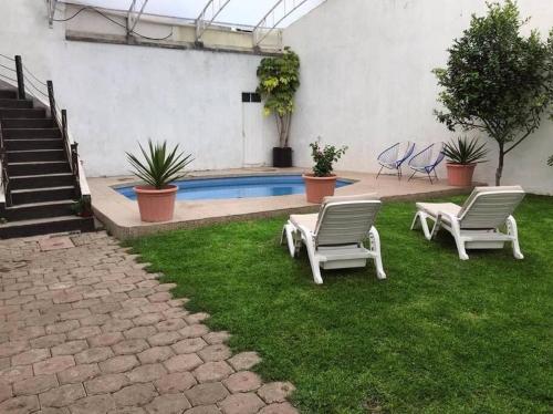 dos sillas sentadas en el césped junto a una piscina en Casa con amplio jardín y alberca, en Tenango de Arista