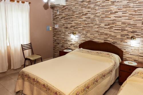 - une chambre avec un lit et un mur en briques dans l'établissement Lo de Hilda, à Villa Elisa
