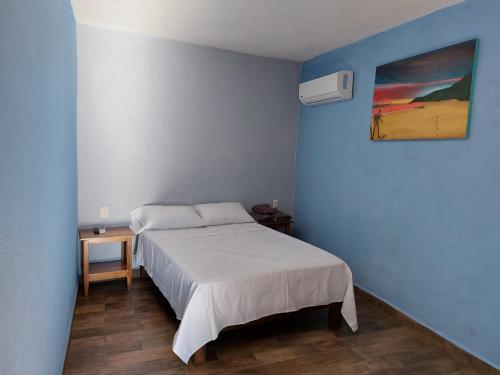 a bedroom with a bed and a painting on the wall at LA CASA AZUL DE SAMARA in Barrio Nuevo