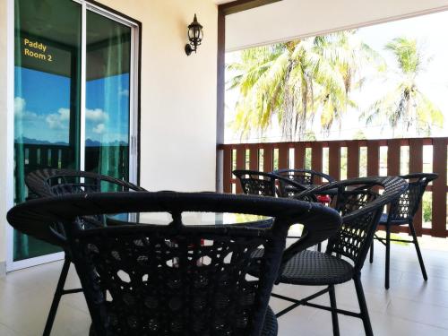 a patio with chairs and a table and a balcony at Haji Hassan Guesthouse in Pantai Cenang