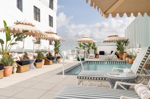 a pool on the roof of a hotel with chairs and umbrellas at Palihouse West Hollywood in Los Angeles