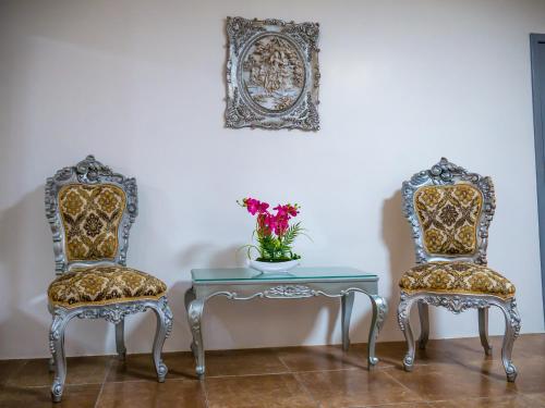 dos sillas y una mesa con un jarrón de flores en The Royalty Inn ApartmentHotel #1 en Guayaquil