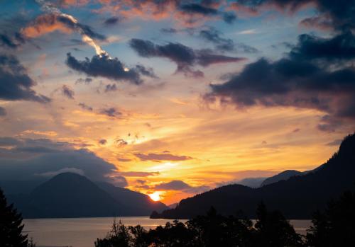 a sunset over a body of water with mountains at Artbliss Hotel in Stevenson
