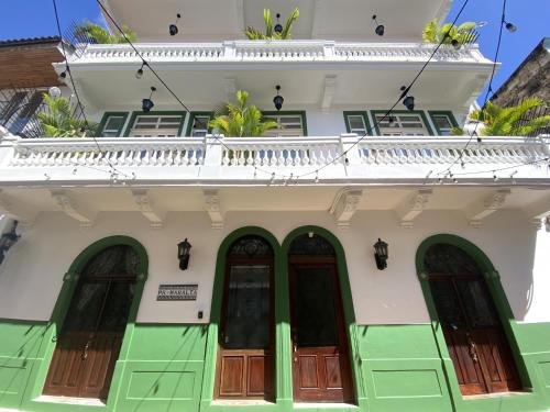 een wit gebouw met groene deuren en een balkon bij AmazINN Places Rooftop and Jacuzzi VII in Panama-Stad