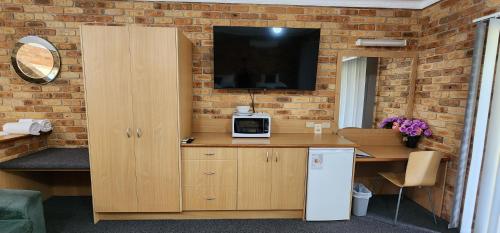 a kitchen with a counter with a tv on a brick wall at Golf Club Motor Inn Wingham in Wingham