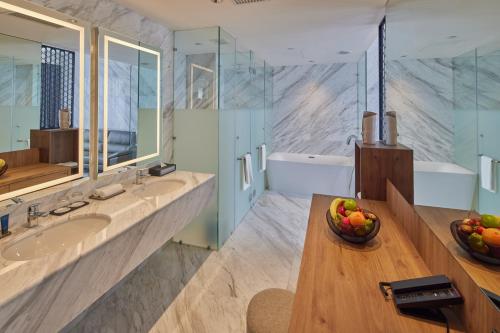 a bathroom with two sinks and a bowl of fruit on a wooden table at Opero Hotel Southkey Johor Bahru in Johor Bahru
